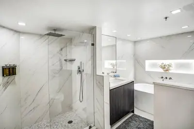 a white bathroom with a shower and a sink at Sunset Hideaway! Direct Water Views and Renovated! in Miami