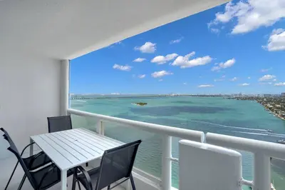a balcony with a table and chairs and the ocean at Cloud Nine! Direct Water Views of Bay & Ocean! in Miami