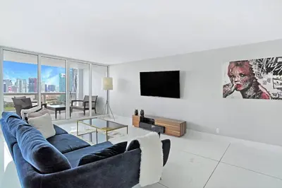 a living room with a blue couch and a tv at Enchanted! Miami Skyline & Water Views in Miami