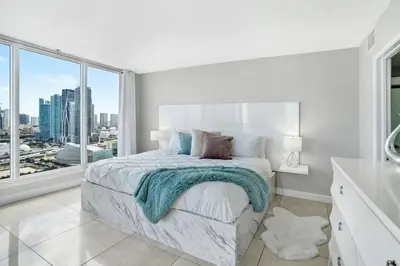 a white bedroom with a bed and a large window at Pisces Dream - Direct water views! in Miami