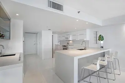 a white kitchen with a sink and stools at Obsession! Water & Park Views in Miami