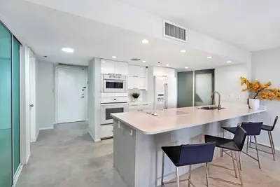 a kitchen with a sink and a counter with chairs at Shore to Please! Park And Water Views! in Miami
