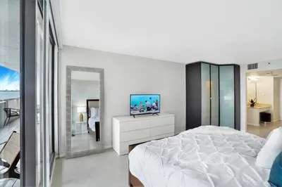 a bedroom with a white bed and a television on a dresser at Shore to Please! Park And Water Views! in Miami