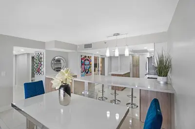 a white kitchen with a table and blue chairs at The Marilyn! Renovated and Amazing Skyline Views! in Miami