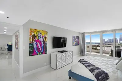 a white bedroom with a bed and a tv at The Marilyn! Renovated and Amazing Skyline Views! in Miami