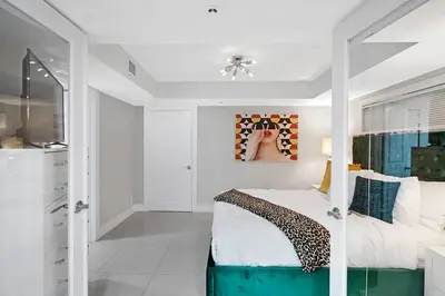 a white bedroom with a bed and a tv at The Marilyn! Renovated and Amazing Skyline Views! in Miami