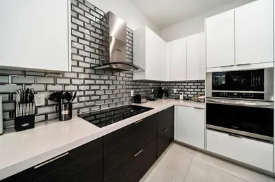 a kitchen with white cabinets and a black and white brick wall at Modern RocknHome Near Hard Rock and FLL Airport in Fort Lauderdale
