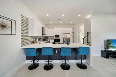 a kitchen with a island with blue bar stools at Modern RocknHome Near Hard Rock and FLL Airport in Fort Lauderdale