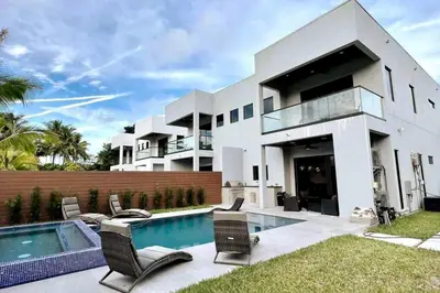 a large white house with a swimming pool and chairs at The Elements Home with 2 Pools in Fort Lauderdale