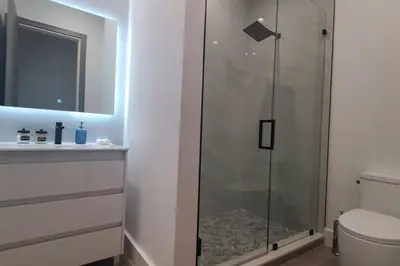 a glass shower in a bathroom with a toilet at The Botanical Oasis Las Olas in Fort Lauderdale