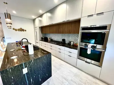 a kitchen with white cabinets and a black counter top at The Botanical Oasis Las Olas in Fort Lauderdale
