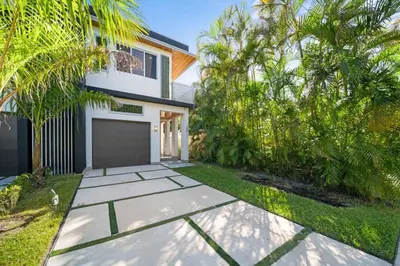 a white house with a garage and palm trees at Las Olas Zen Home with Pool and Hot Tub Near Beach in Fort Lauderdale