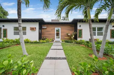 a house with palm trees and a walkway at Newly Renovated Tropical Oasis Near Las Olas Beach in Fort Lauderdale