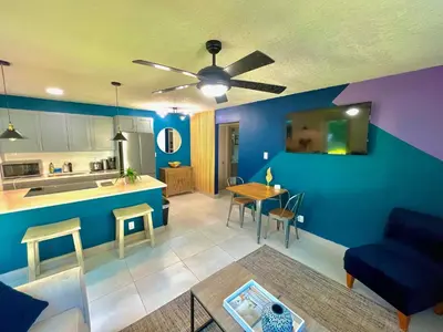 a living room and kitchen with a blue wall at SuaveMauve Las Olas Beach in Fort Lauderdale