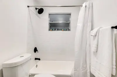 a white bathroom with a toilet and a window at Airport Loft 1b full kitchen Virg 10 in Miami
