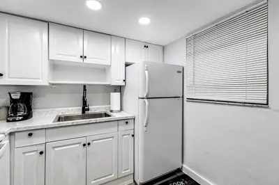 a kitchen with white cabinets and a white refrigerator at Airport Loft 1b full kitchen Virg 10 in Miami