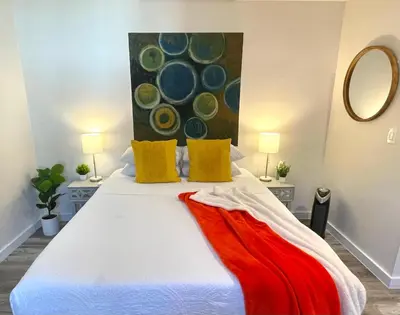 a bedroom with a white bed with a painting on the wall at The Agustin Guesthouse - Men Only Clothing Optional in Fort Lauderdale