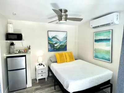 a small bedroom with a bed with yellow pillows at The Agustin Guesthouse - Men Only Clothing Optional in Fort Lauderdale