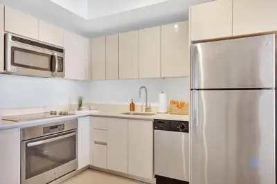 a kitchen with white cabinets and a stainless steel refrigerator at Amazing Pool - Apartment with Balcony and Gym in Hallandale Beach