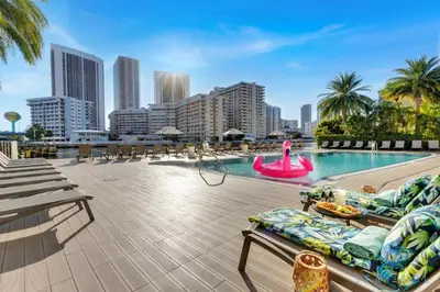 a swimming pool with chaise lounges and a pink poolvisorvisorvisor at Infinite View Balcony - Amazing Pool - Gym in Hallandale Beach