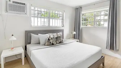 a white bedroom with a bed and two windows at Brickell Pearl Cozy House Beach 10 min Location in Miami