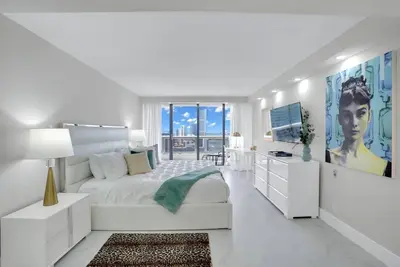 a white bedroom with a large bed and a television at Superstar! Penthouse with Water and Park Views! in Miami