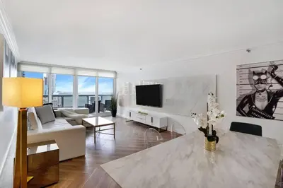 a white living room with a couch and a tv at Magic City! Water And Park Views! in Miami