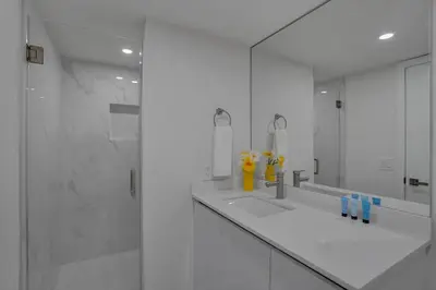 a white bathroom with two sinks and a mirror at Elevate! Water and Park Views in Miami