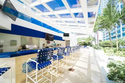 a row of blue chairs at a bar at a resort at Some Like It Hot! Miami Skyline & Water Views 4BR in Miami