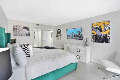 a white bedroom with a large white bed and a chair at Life Is Gucci! Gorgeous WATER VIEWS Miami Condo! in Miami