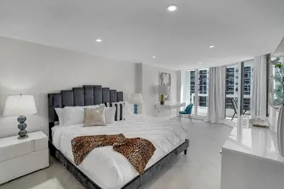 a white bedroom with a large bed with a leopard blanket at Visions! Water and Miami Skyline VIews! Brand New in Miami