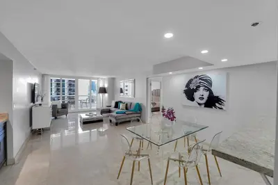 a white living room with a glass table and chairs at Hello Gorgeous! Water & City Skyline Views! in Miami