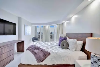 a white bedroom with a large bed and a television at Summer Retreat! Water and City Views! in Miami