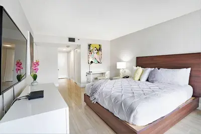 a white bedroom with a large bed and a desk at Day Dreamer! Water & Miami City Views! in Miami
