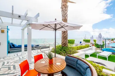 a patio with a table and chairs and an umbrella at Oceanview Luxury, Resort Access, Sleeps 6 2BR 2BA - Vista Mar by HomeStakes Stays in Fort Lauderdale