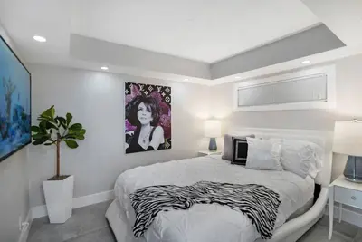 a white bedroom with a zebra print bed and a painting at Blue Moon! In the lap of luxury and brand new! in Miami