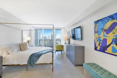 a bedroom with a king sized bed and a chair at Sweet Dreams! Renovated with Water Views in Miami