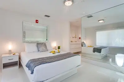 a white bedroom with a large bed and a bathroom at Bars B&B South Beach Hotel in Miami Beach