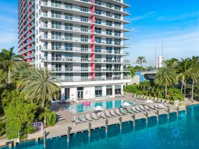 a hotel with a pool and chairs and a building at Sunset Oasis with 2BR, Balcony, Pool, Perfect Getaway in Hallandale Beach