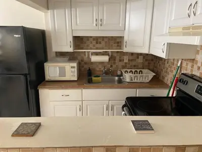 a kitchen with white cabinets and a black refrigerator at Cozy Private House near Miami Airport - Free parking - 02 in Miami