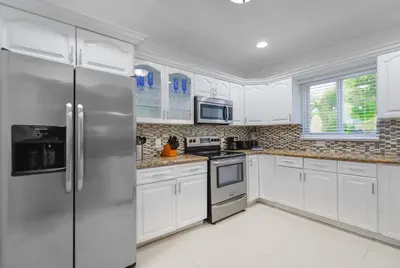 a kitchen with white cabinets and a stainless steel refrigerator at Discover Serenity in this Tranquil Miami Home in Miami