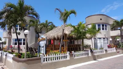 a building with a white fence and palm trees at Caribbean Resort by the Ocean in Hollywood