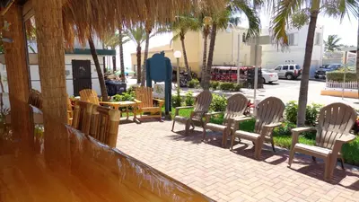 a group of chairs sitting on a sidewalk with palm trees at Caribbean Resort by the Ocean in Hollywood