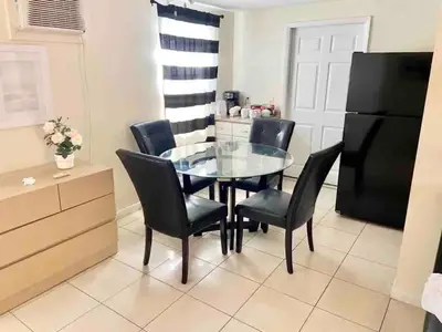 a dining room with a glass table and black chairs at Cozy rooms in cute house, close to Miami airport - Free parking in Miami