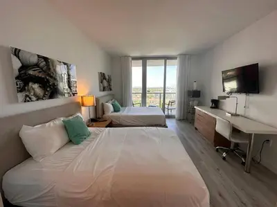 a hotel room with two beds and a desk and a computer at Seaside Studio Comfort Great for Small Groups in Hallandale Beach