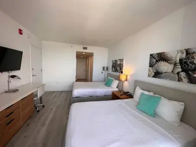 a hotel room with two beds and a flat screen tv at Seaside Studio Comfort Great for Small Groups in Hallandale Beach
