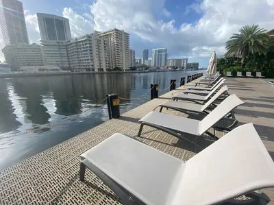 a row of white lounge chairs next to the water at Seaside Studio Comfort Great for Small Groups in Hallandale Beach