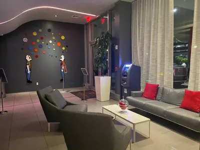 a living room with couches and a wall with a clock at Seaside Studio Comfort Great for Small Groups in Hallandale Beach