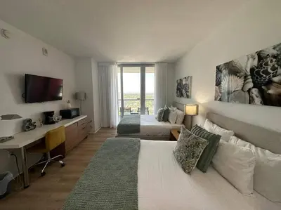 a bedroom with two beds and a desk with a computer at Studio with 2 Full Beds, Perfect Beach Location in Hallandale Beach