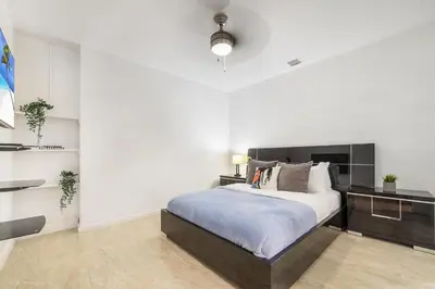 a bedroom with a large bed and a white wall at The Palms -Mini Golf , Foosball Table, Heated Pool ,Baby items ,BBQ in Miami